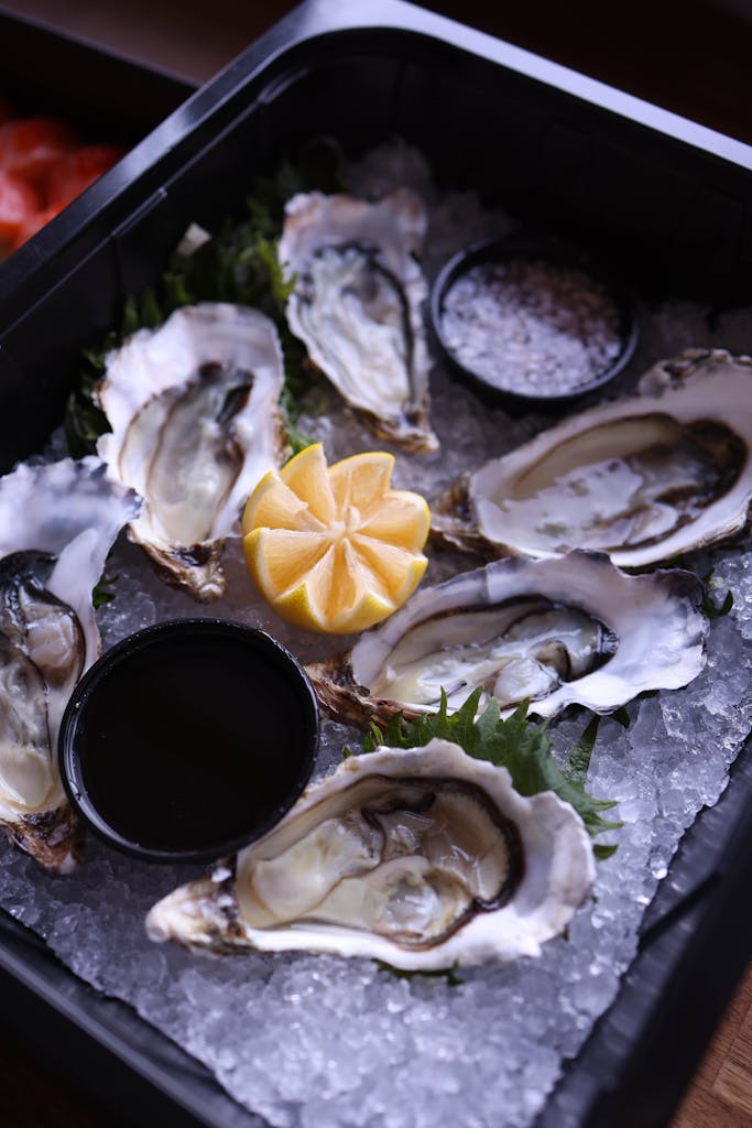 A tray of fresh oysters on ice, garnished with lemon wedges, ready to serve.