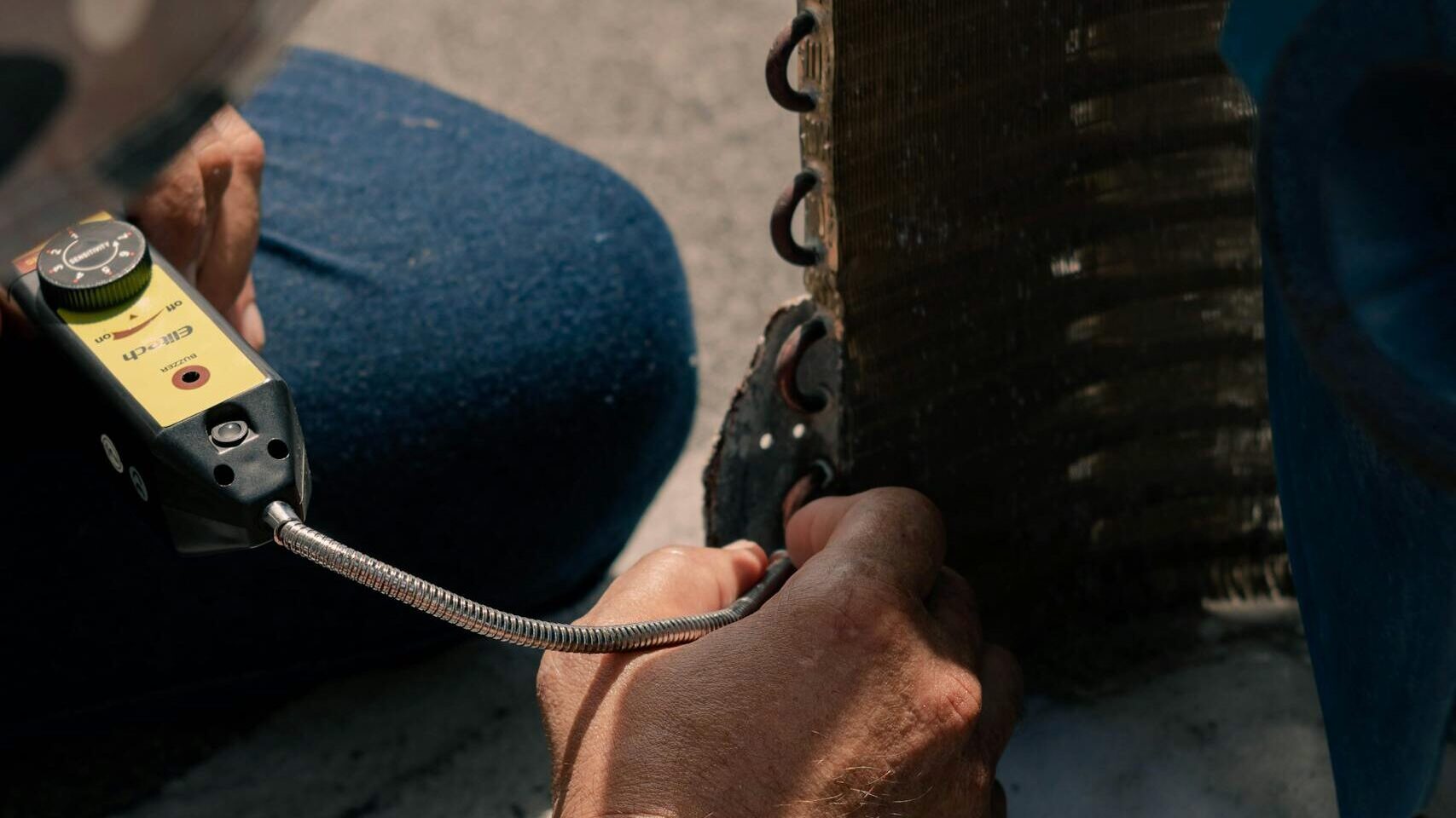 Technician repairing an air conditioner unit with tools, showcasing detailed maintenance process.